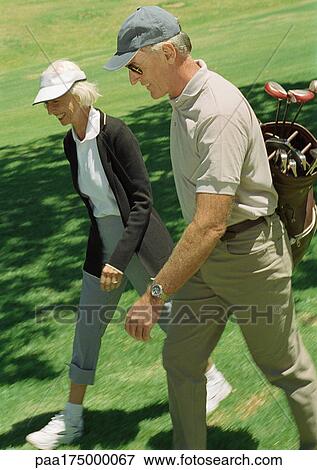 Mature man and woman on green, man carrying golf clubs View Large Photo Image Stock Photo - Mature man and woman on green, man carrying golf clubs. Fotosearch