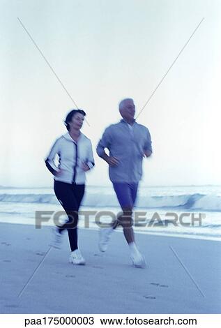 Mature man and woman running on beach View Large Photo Image Stock Image - Mature man and woman running on beach. Fotosearch