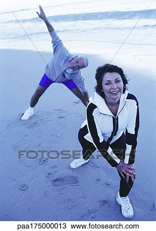 Mature man and woman stretching on beach View Large Photo Image Stock Image - Mature man and woman stretching on beach. Fotosearch