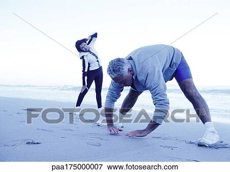 Mature man and woman stretching on beach View Large Photo Image Stock Photo - Mature man and woman stretching on beach. Fotosearch