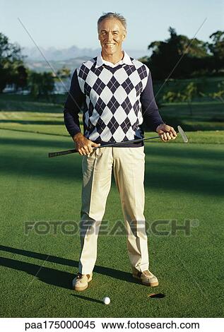 Mature man holding golf club next to hole, portrait View Large Photo Image Stock Photography - Mature man holding golf club next to hole, portrait. Fotosearch