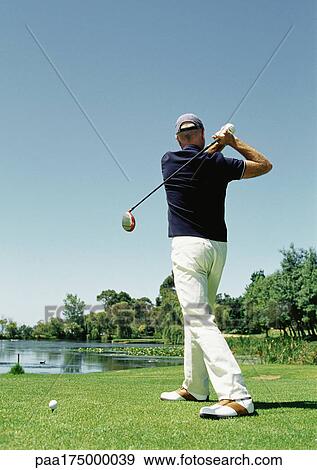 Stock Photo - Mature man playing golf, rear view. Fotosearch