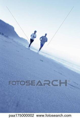 Stock Image - People running on beach, blurred. Fotosearch