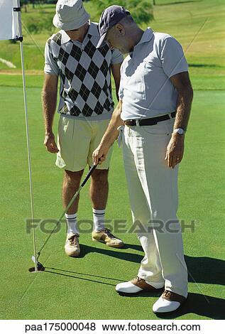 Two mature golfers looking at hole View Large Photo Image Stock Photo - Two mature golfers looking at hole. Fotosearch