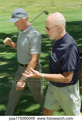 Stock Photo - Two mature golfers walking on green. Fotosearch