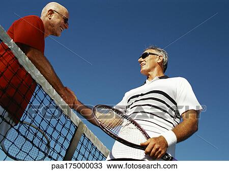 Two mature men shaking hands over tennis net, low angle view View Large Photo Image Stock Image - Two mature men shaking hands over tennis net, low angle view. Fotosearch