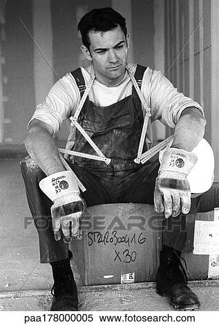 Builder with folding ruler around neck, sitting on cardboard box, b&w View Large Photo Image Stock Photography - Builder with folding ruler around neck, sitting on cardboard box, b&w. Fotosearch