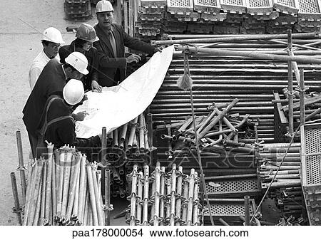Five people examining blueprints in construction site, b&w View Large Photo Image Picture - Five people examining blueprints in construction site, b&w. Fotosearch