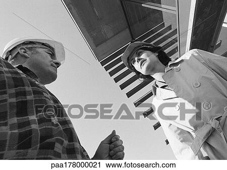 Man and woman wearing hard hats, low angle view View Large Photo Image Stock Image - Man and woman wearing hard hats, low angle view. Fotosearch