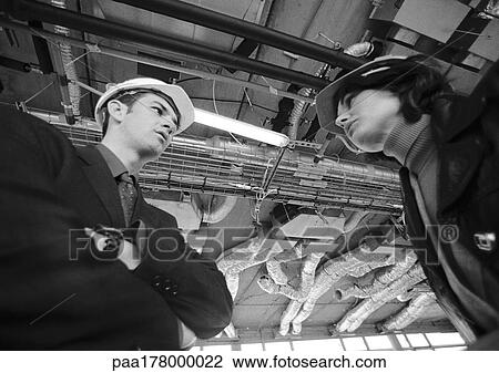 Man and woman wearing hard hats, low angle view View Large Photo Image Stock Image - Man and woman wearing hard hats, low angle view. Fotosearch