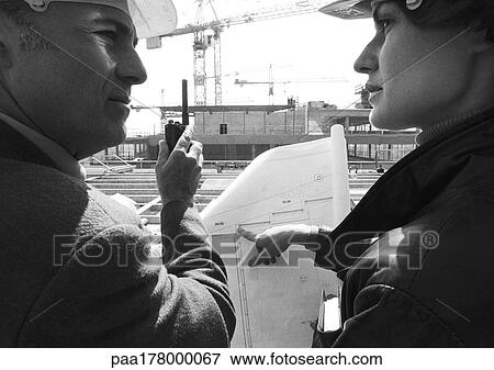 Man and woman with hard hats, examining blueprints, close-up, b&w View Large Photo Image Stock Photo - Man and woman with hard hats, examining blueprints, close-up, b&w. Fotosearch
