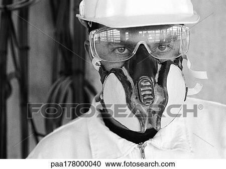 Stock Image - Man wearing hard hat, dust mask and glasses, close-up, b&w. Fotosearch