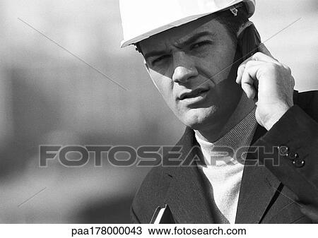 Man with hard hat using cell phone, close-up, b&w View Large Photo Image Stock Image - Man with hard hat using cell phone, close-up, b&w. Fotosearch