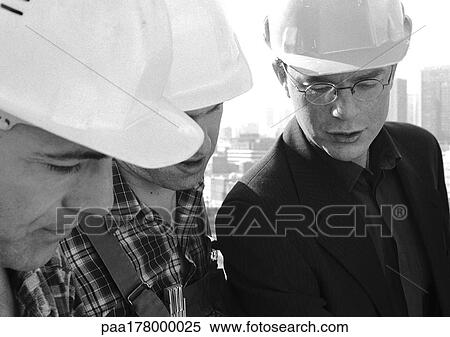 Stock Photography - Three men wearing hard hats, close-up, b&w. Fotosearch