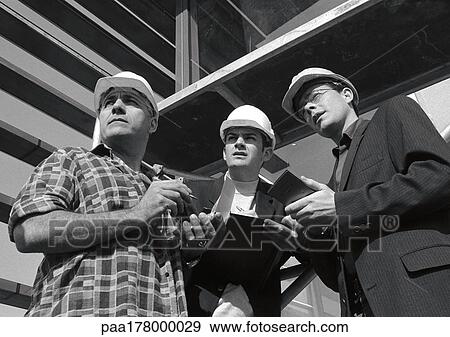 Three men wearing hard hats, holding notepads, b&w View Large Photo Image Stock Photo - Three men wearing hard hats, holding notepads, b&w. Fotosearch