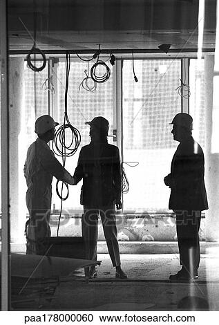 Three people with hard hats, two shaking hands, b&w View Large Photo Image Stock Image - Three people with hard hats, two shaking hands, b&w. Fotosearch