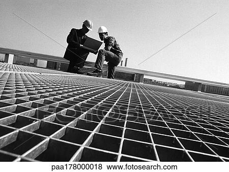 Two men wearing hard hats, looking at laptop computer, b&w View Large Photo Image Stock Photo - Two men wearing hard hats, looking at laptop computer, b&w. Fotosearch