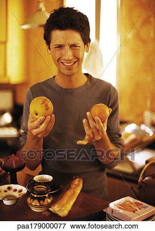 Man holding up fruit and making face, portrait View Large Photo Image Stock Photo - Man holding up fruit and making face, portrait. Fotosearch