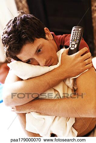 Man hugging pillow and holding remote control View Large Photo Image Stock Image - Man hugging pillow and holding remote control. Fotosearch