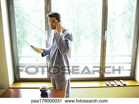 Man in pajamas using cell phone and reading newspaper View Large Photo Image Stock Image - Man in pajamas using cell phone and reading newspaper. Fotosearch