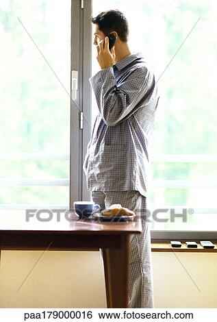 Stock Photograph - Man in pajamas using cell phone. Fotosearch