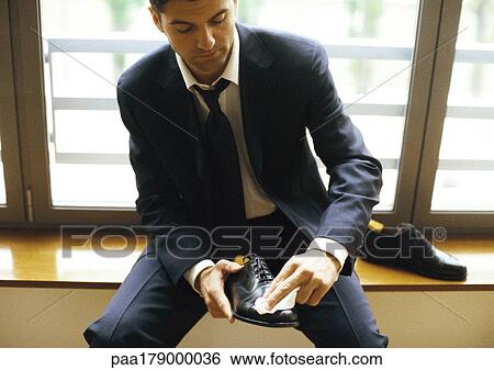 Man in suit polishing shoe, close-up View Large Photo Image Stock Photograph - Man in suit polishing shoe, close-up. Fotosearch