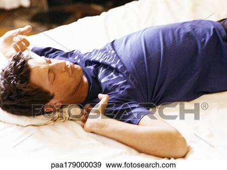 Man lying on bed View Large Photo Image Stock Photo - Man lying on bed. Fotosearch