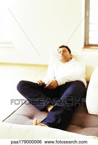 Stock Photograph - Man lying on sofa, blurred. Fotosearch