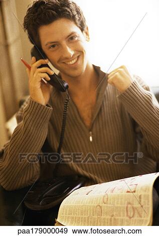 Stock Photo - Man phoning with newspaper on knees, smiling. Fotosearch