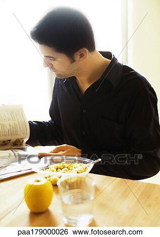 Stock Photograph - Man reading and eating. Fotosearch