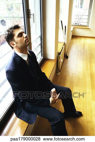 Man sitting against window with head back and eyes closed View Large Photo Image Stock Photo - Man sitting against window with head back and eyes closed. Fotosearch