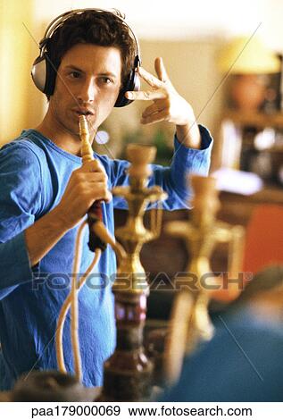 Man wearing headphones, holding hookah like a microphone View Large Photo Image Stock Photo - Man wearing headphones, holding hookah like a microphone. Fotosearch
