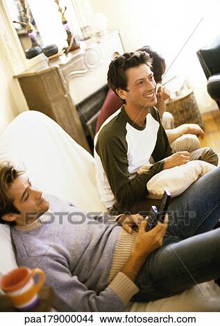 Men sitting on sofa, smiling View Large Photo Image Picture - Men sitting on sofa, smiling. Fotosearch