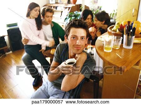 Young people in living room, man having coffee View Large Photo Image Stock Photo - Young people in living room, man having coffee. Fotosearch
