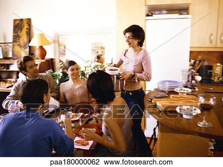 Four people sitting at table, woman bringing dish View Large Photo Image Stock Image - Four people sitting at table, woman bringing dish. Fotosearch
