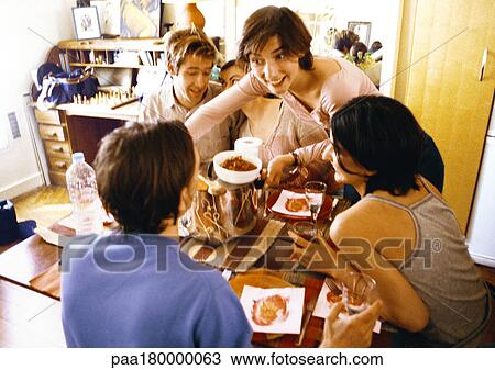 Four people sitting at table, woman bringing dish View Large Photo Image Stock Image - Four people sitting at table, woman bringing dish. Fotosearch