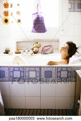 Stock Image - Woman in bathtub, looking up, side view. Fotosearch