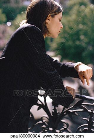 Woman leaning on balcony railing, looking at watch, close-up View Large Photo Image Picture - Woman leaning on balcony railing, looking at watch, close-up. Fotosearch