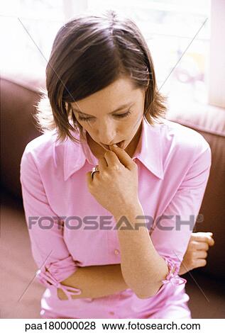 Woman looking down with finger in mouth View Large Photo Image Stock Photo - Woman looking down with finger in mouth. Fotosearch