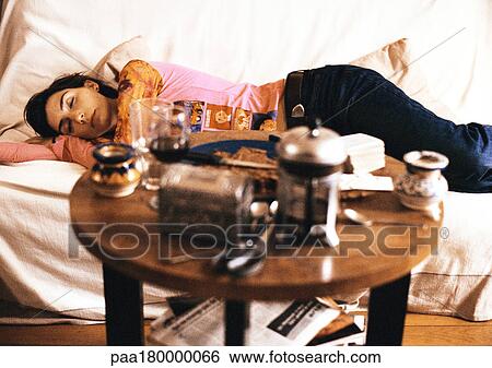 Stock Photograph - Woman lying on sofa with eyes closed. Fotosearch