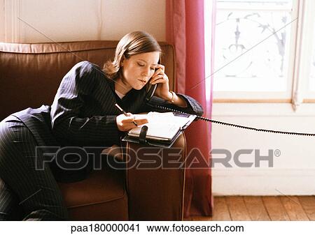 Stock Image - Woman on phone looking at agenda. Fotosearch