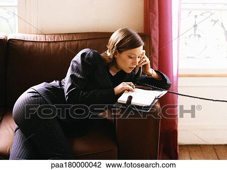 Stock Image - Woman on phone looking at agenda. Fotosearch