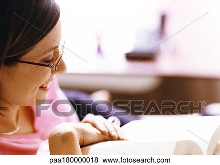Woman reading book, smiling, close-up View Large Photo Image Stock Photo - Woman reading book, smiling, close-up. Fotosearch