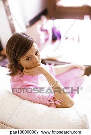 Stock Photo - Woman sitting on sofa. Fotosearch