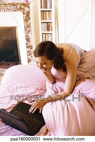 Woman using laptop computer on bed View Large Photo Image Stock Image - Woman using laptop computer on bed. Fotosearch