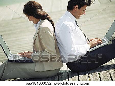 Businessman and woman back to back on ground with laptop computers on laps View Large Photo Image Stock Image - Businessman and woman back to back on ground with laptop computers on laps. Fotosearch