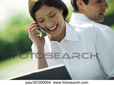 Businessman and woman back to back, woman using cell phone, head and shoulders, tilt View Large Photo Image Picture - Businessman and woman back to back, woman using cell phone, head and shoulders, tilt. Fotosearch
