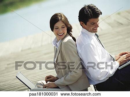 Businessman and woman back to back with laptop computers, waist up, tilt View Large Photo Image Stock Image - Businessman and woman back to back with laptop computers, waist up, tilt. Fotosearch