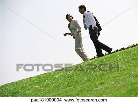 Picture - Businessman and woman walking on grass. Fotosearch