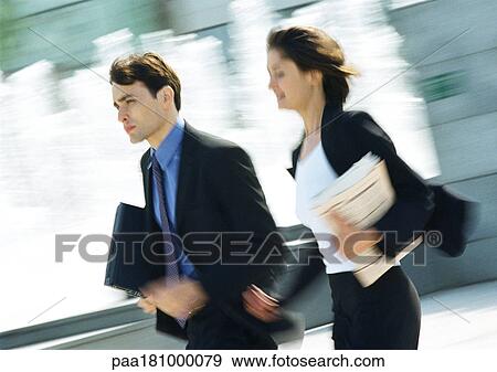 Businessman and woman walking outdoors, blurred motion View Large Photo Image Stock Photo - Businessman and woman walking outdoors, blurred motion. Fotosearch
